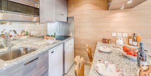 Uma cozinha moderna com eletrodomésticos de aço inoxidável, bancadas de granito e armários de madeira.