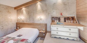 A bedroom with a wooden headboard, a white dresser, and a nightstand with a lamp. - 20m from resort center, 6th floor, balcony, tv, ski locker, 55m², Tignes (Tignes)