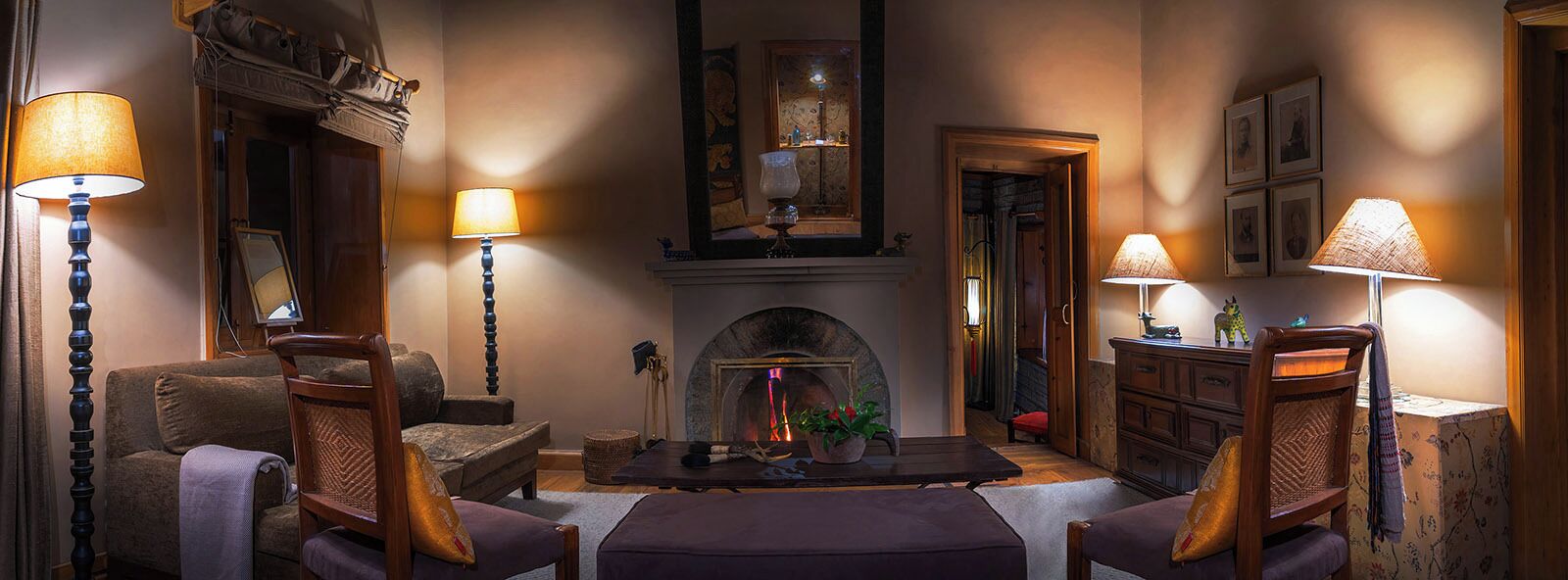 A cozy living room with a fireplace, wooden furniture, and lamps.