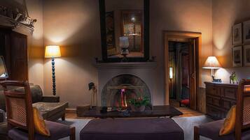 A cozy living room with a fireplace, wooden furniture, and lamps.