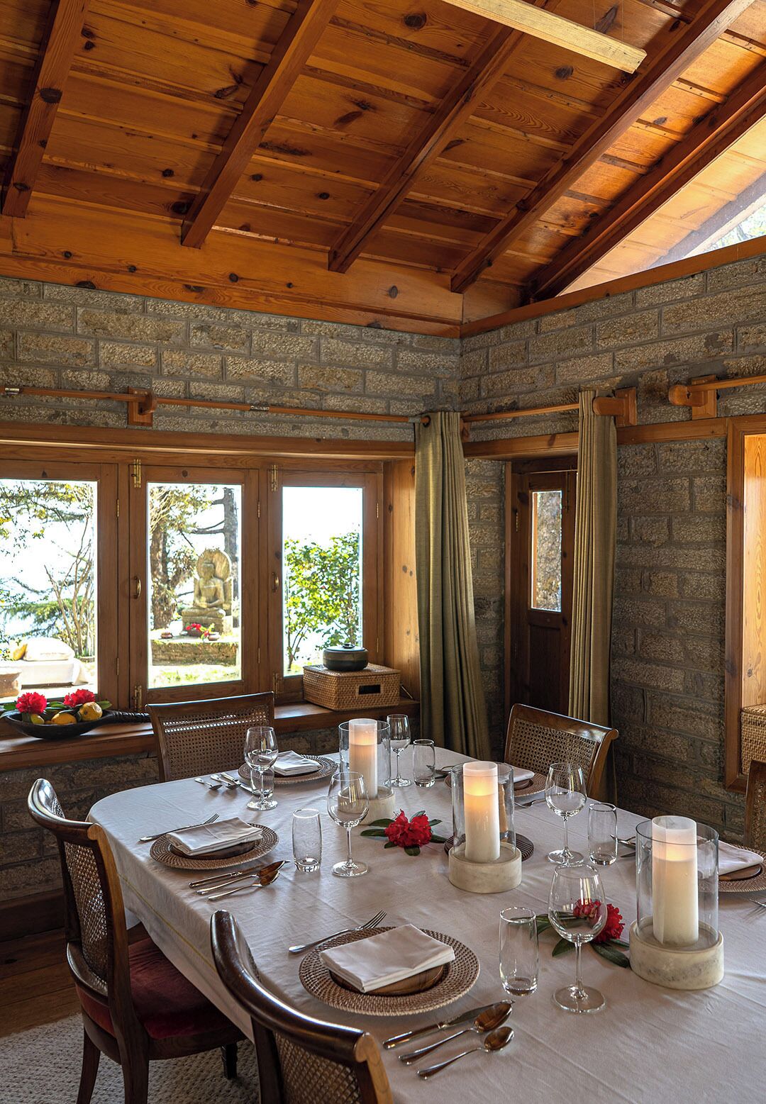 A dining area with a wooden ceiling, stone walls, and large windows.