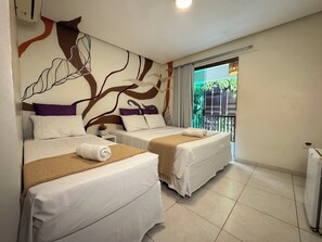 Habitación de hotel con dos camas, un mural decorativo, un balcón con vistas a la vegetación y un radiador blanco.