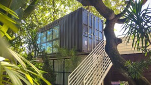 A modern building with a staircase leading to an upper level, surrounded by lush greenery. - Pousada Unaí (Ipojuca)