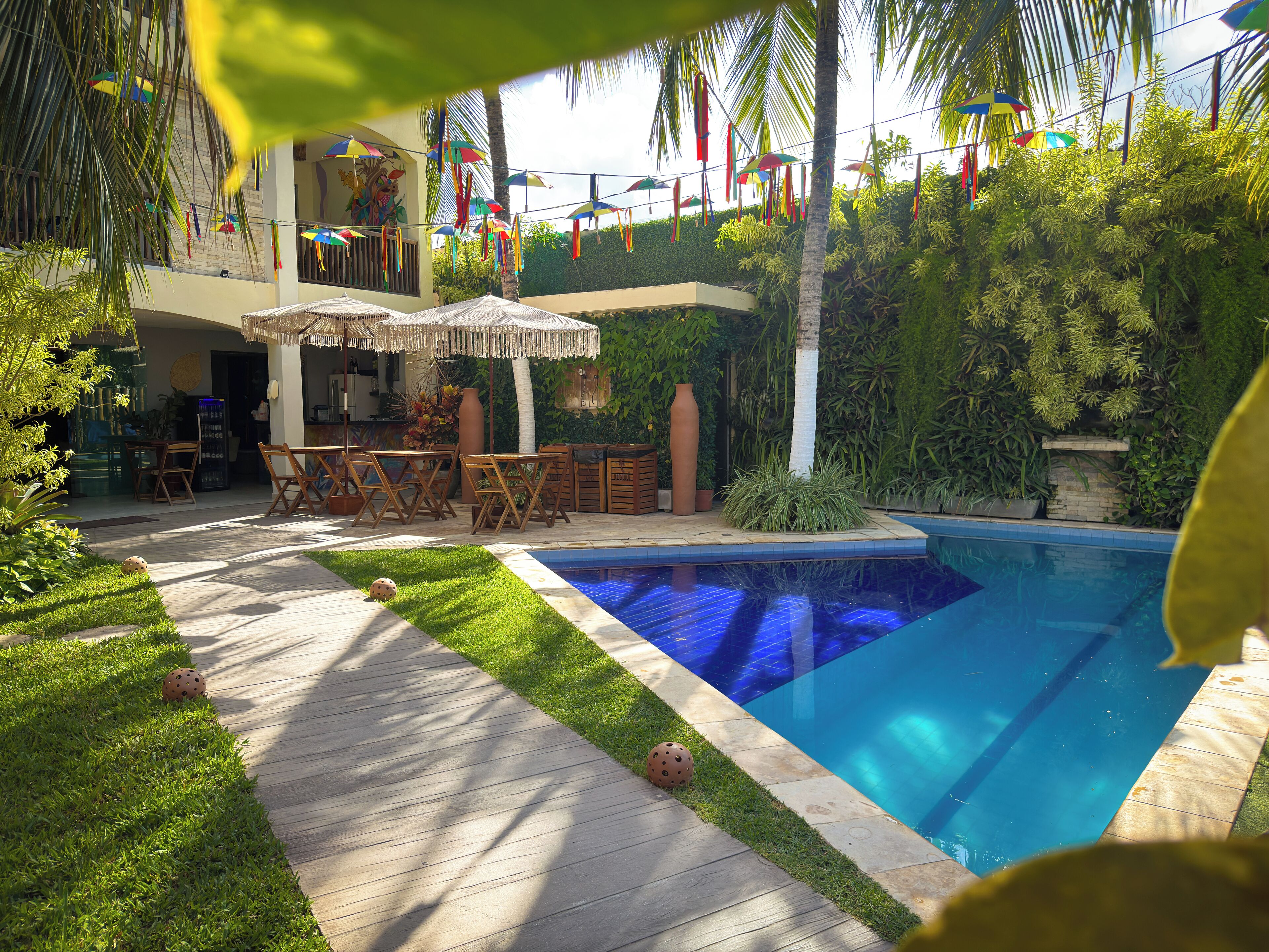 A pool area with a wooden deck, outdoor furniture, and a variety of umbrellas.