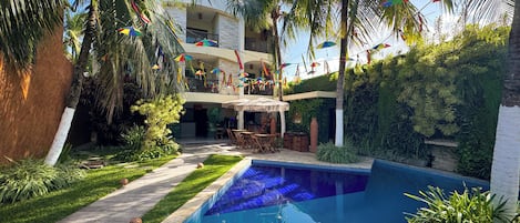 Una piscina al aire libre, sombrillas, sillones reclinables de piscina