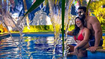 Una piscina al aire libre, sombrillas, sillones reclinables de piscina