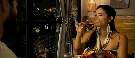 A dining table with a candle, wine glass, and a bouquet of flowers.