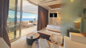 Une chambre d’hôtel moderne dotée d’un balcon, d’un lit, d’une télévision et d’un coin salon avec une table et des chaises.