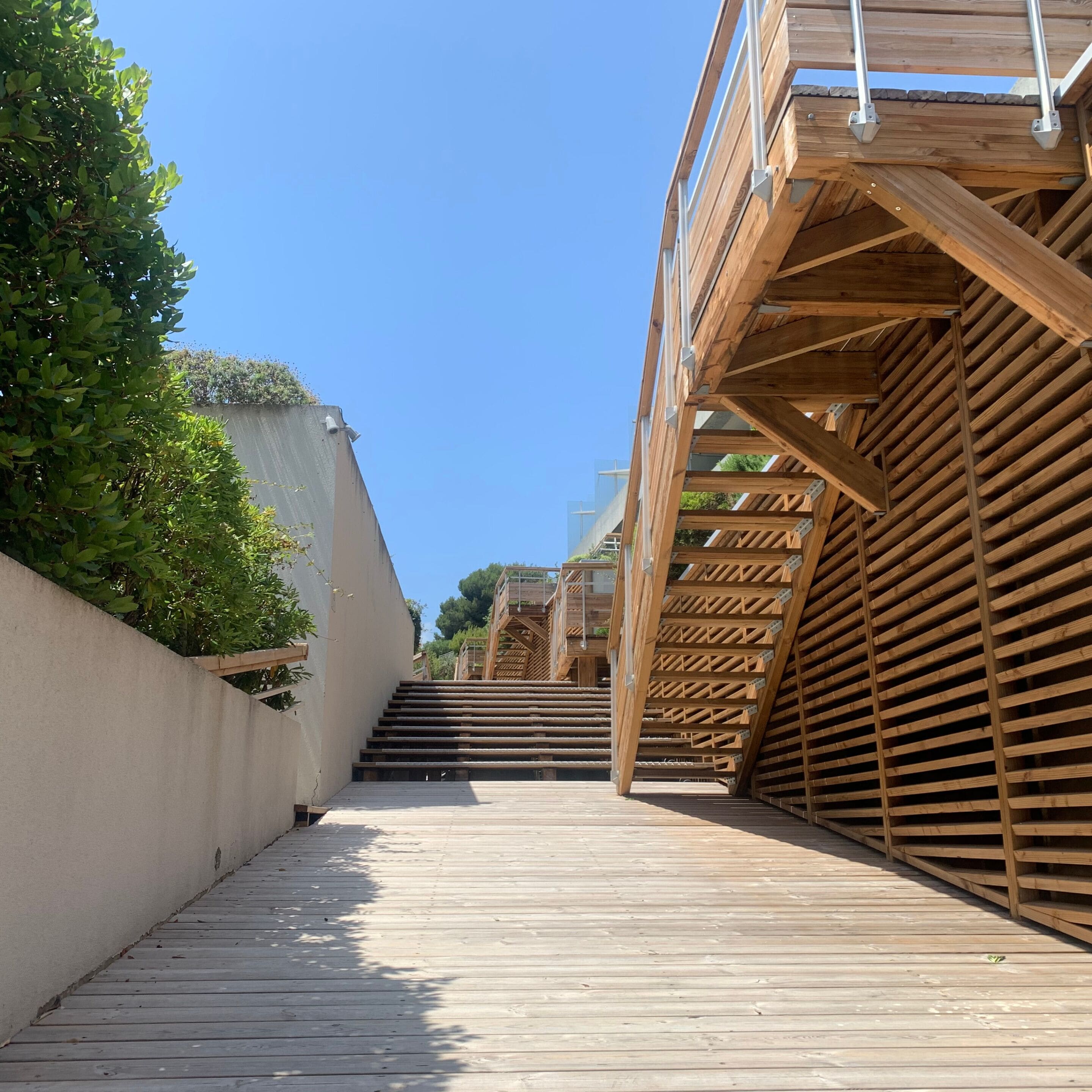 Un escalier en bois menant à un balcon doté d’une rambarde en métal.