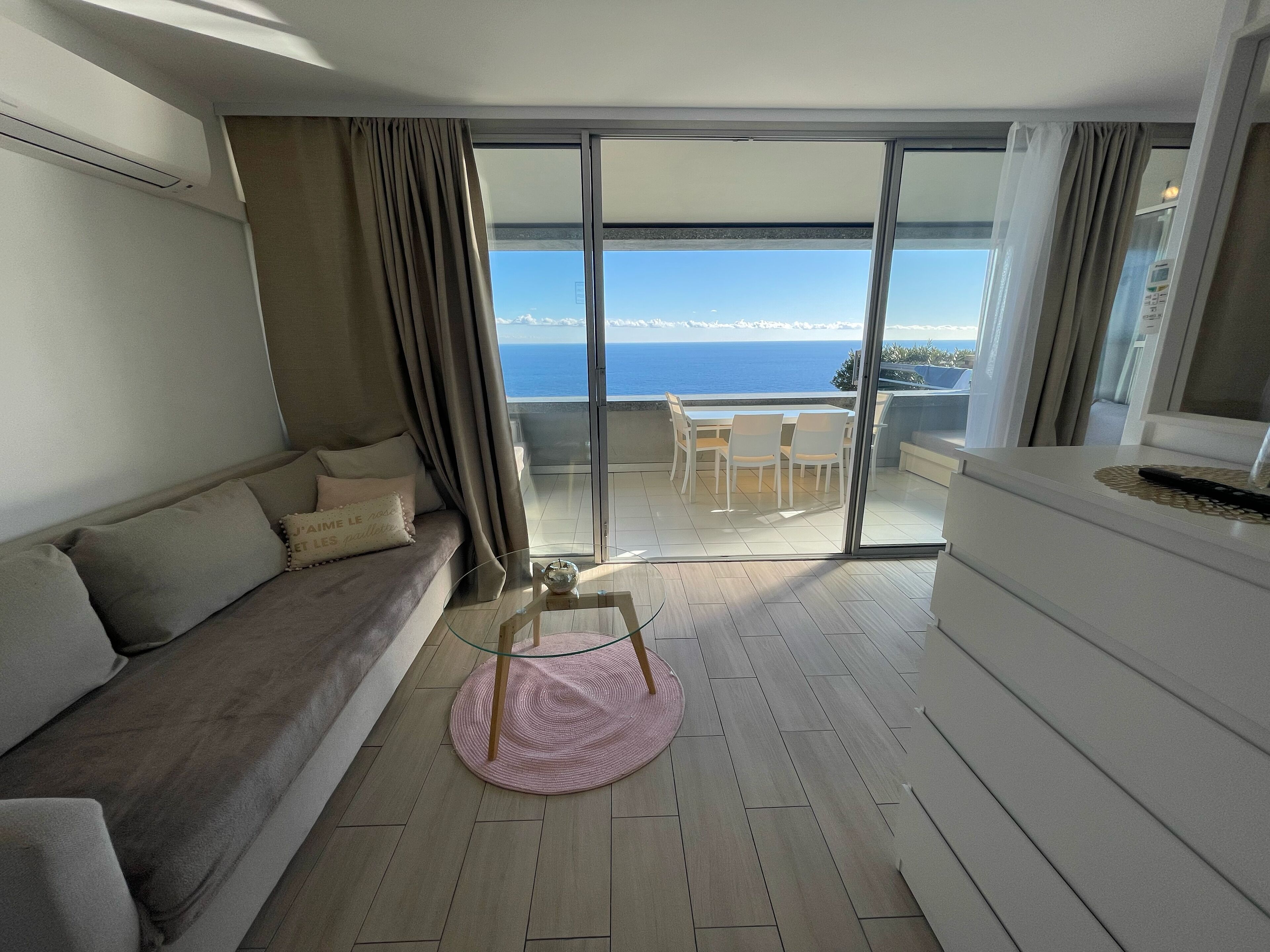 A balcony with a view of the sea, a sofa, a table, and a chair.