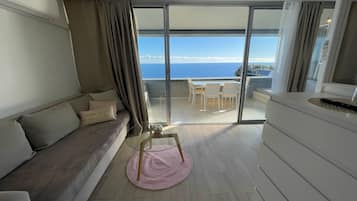 A balcony with a view of the sea, a sofa, a table, and a chair.
