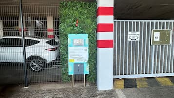 Un aparcament amb un cotxe blanc a dins, una càmera de seguretat i un senyal que indica vigilància.