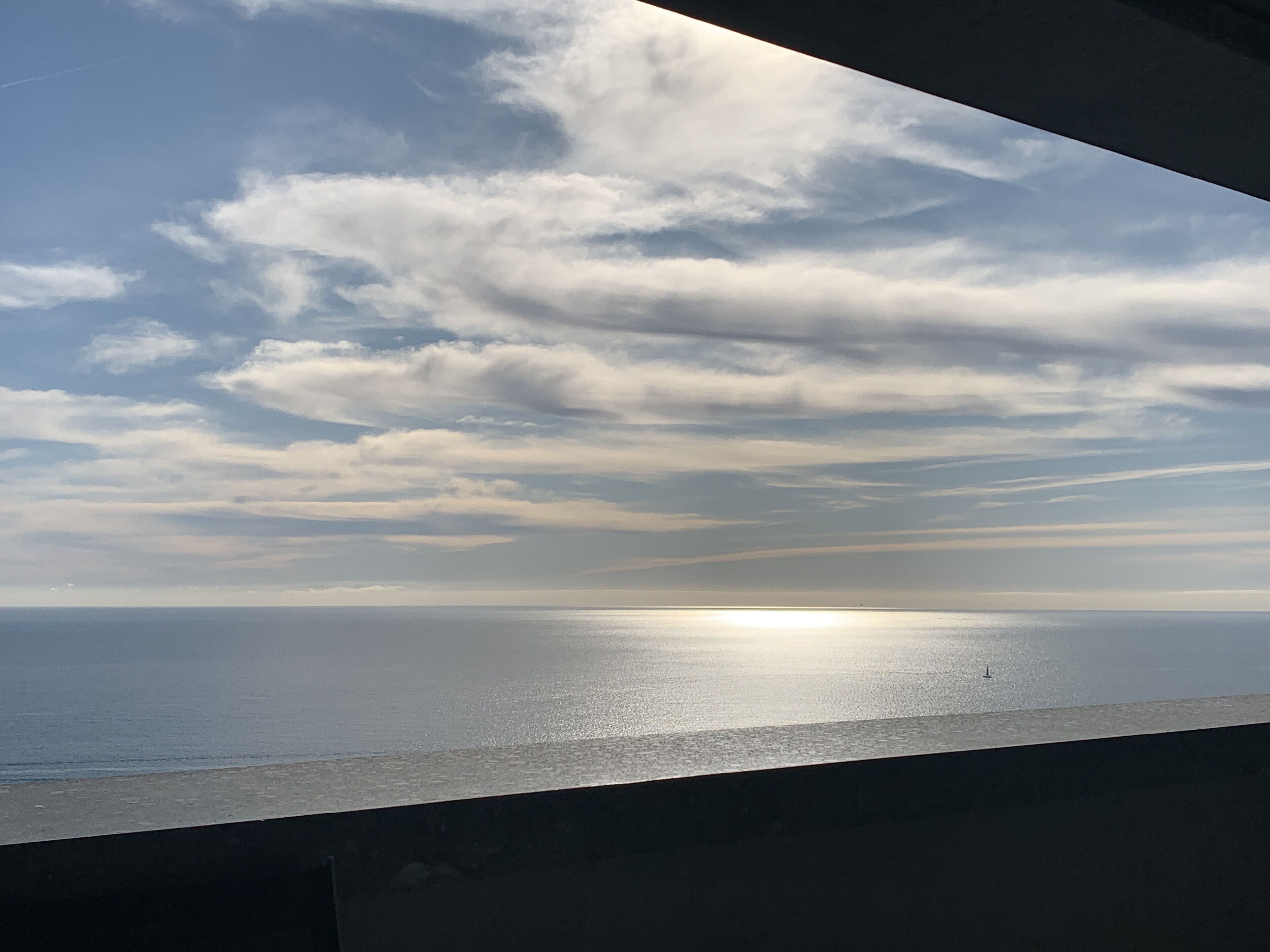 A view of the ocean with a clear sky and clouds.