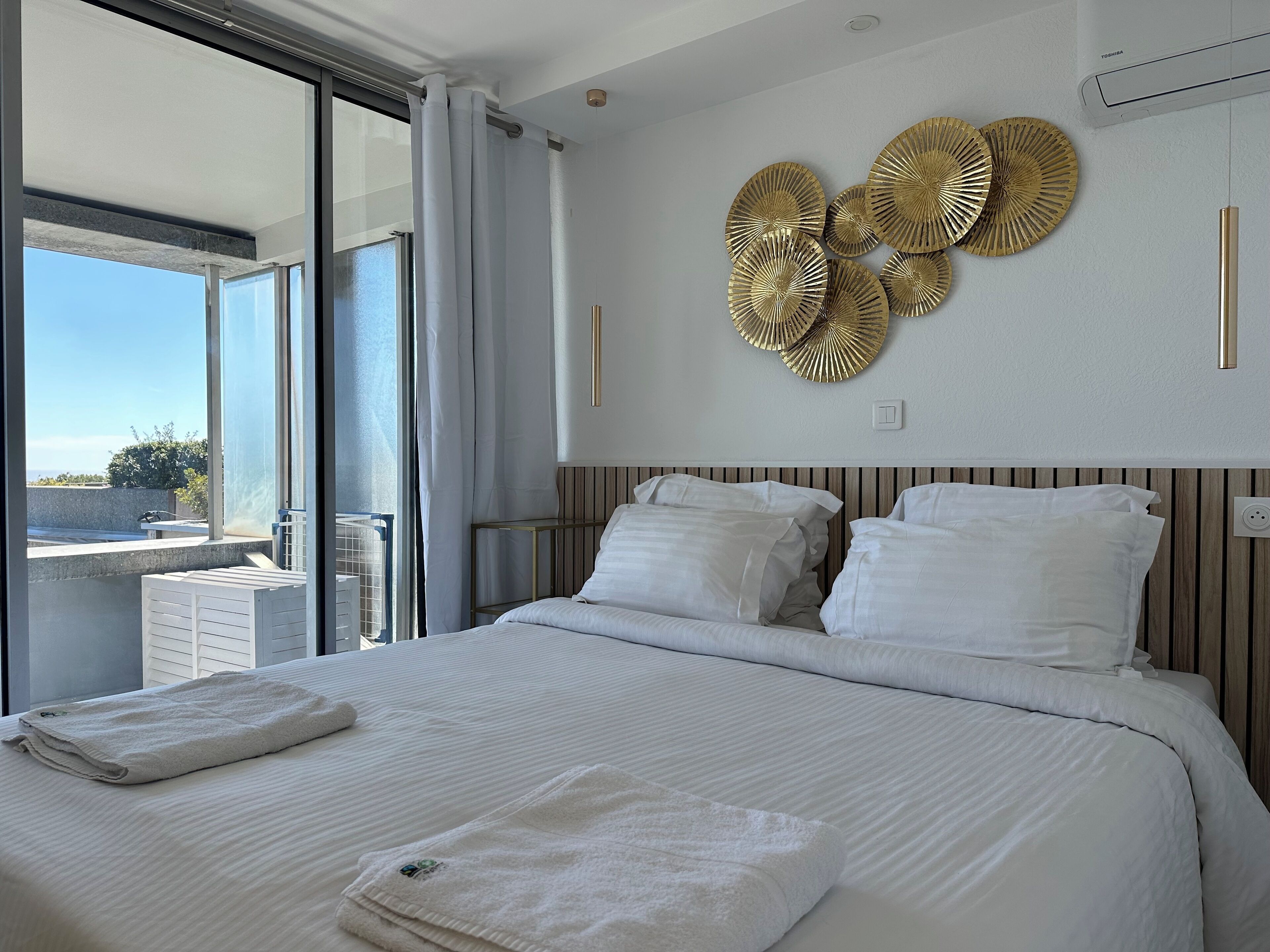 A hotel room with a large bed, a balcony with a view, and decorative wall art.