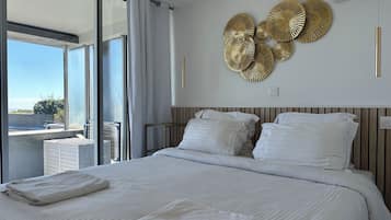 A hotel room with a large bed, a balcony with a view, and decorative wall art.