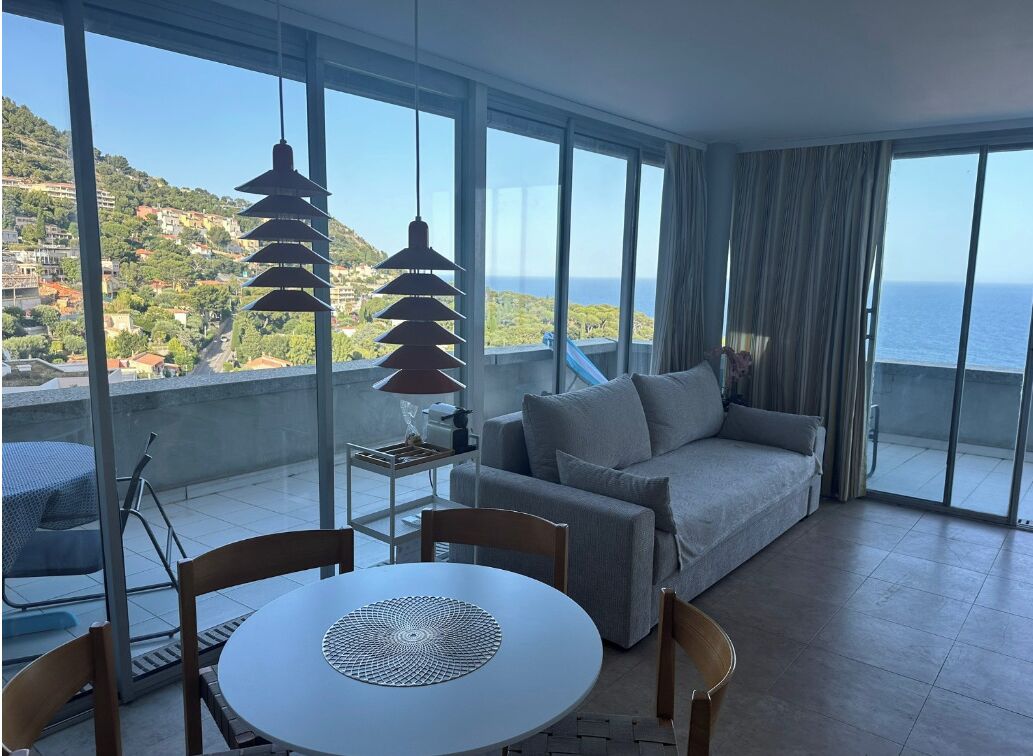 Ein Balkon mit einer Sitzecke, einem Tisch und Stühlen mit Blick auf die Küste.