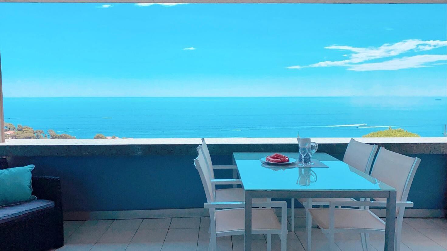 Un balcon avec une table et des chaises donnant sur une vue imprenable sur la mer.