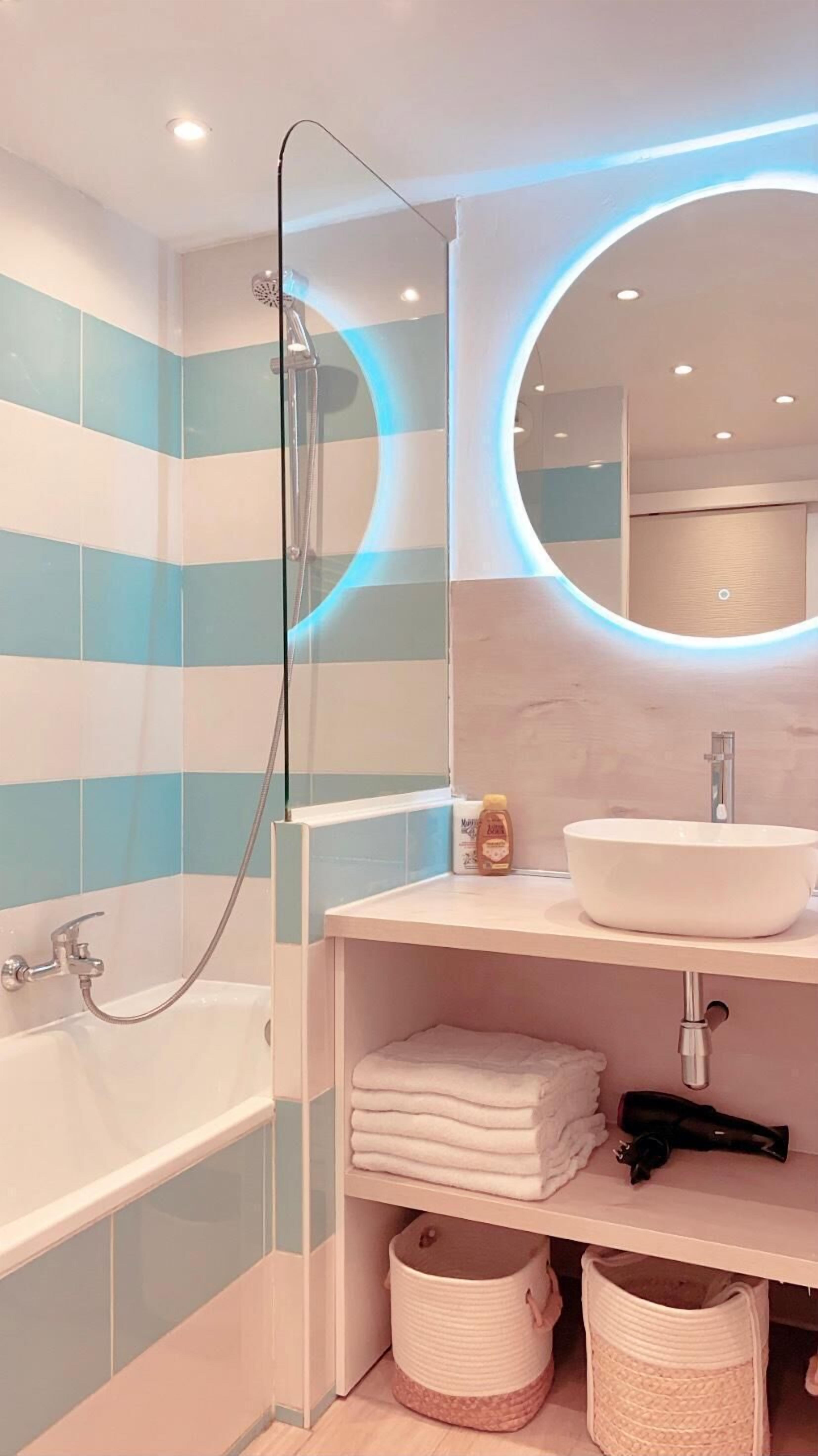 Een moderne badkamer met een douche, wastafel en spiegel.