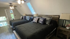 Camera da letto con due letti, una ventola a soffitto, un lucernario e pavimento in legno.