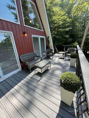 Een houten terras met tuinmeubilair, waaronder een bank en stoelen, en een potplant.