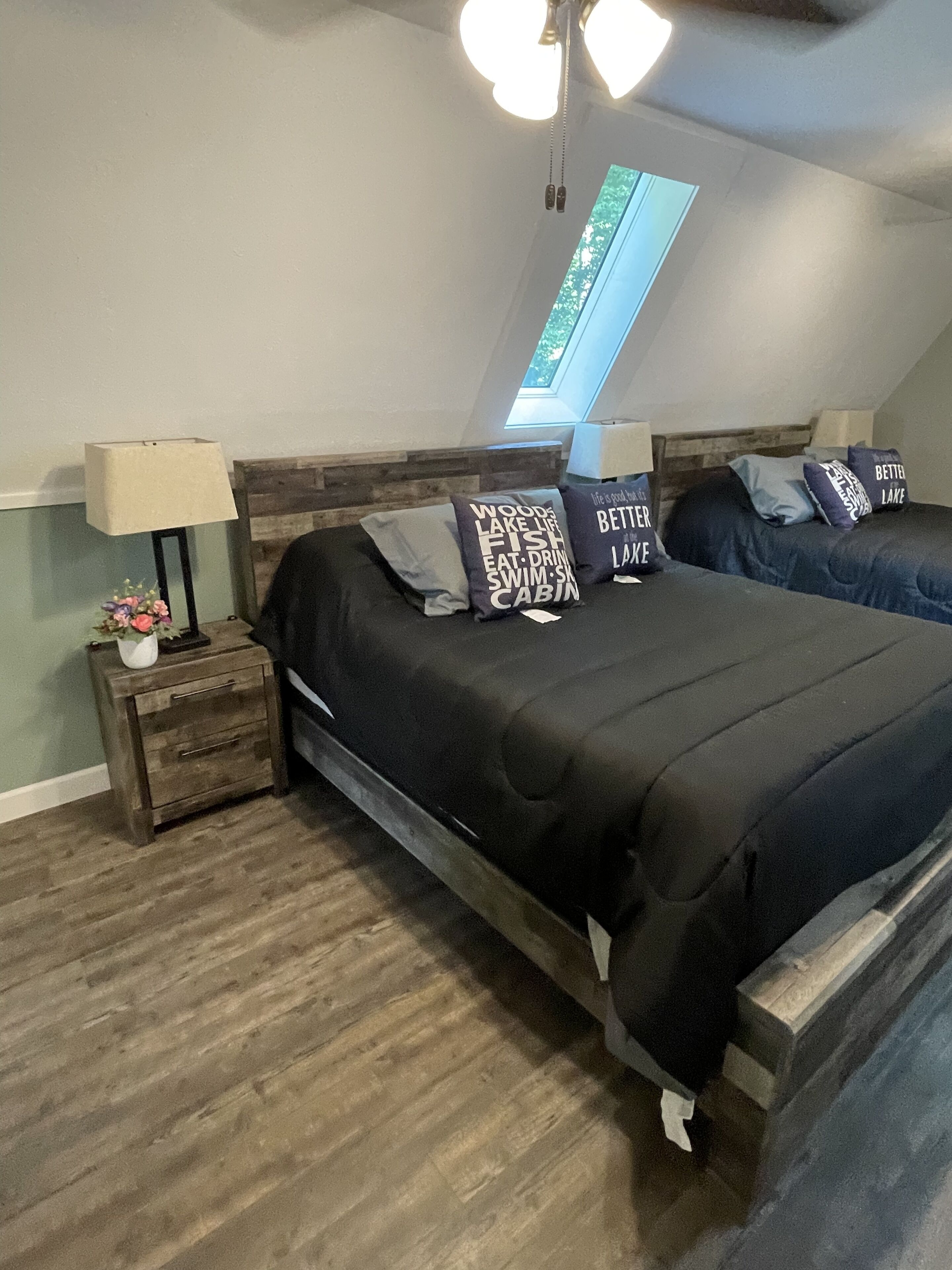 Ein Schlafzimmer mit einem großen Bett, zwei Nachttischen, einer Lampe und Seeblick durch ein Oberlicht.