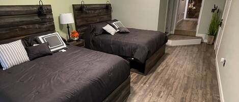 Un dormitorio con dos camas, un ventilador de techo y una mesita de noche con una lámpara.
