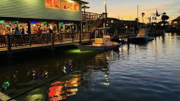 A waterfront restaurant with outdoor seating, a dock, and a boat. - Beautiful island paradise only 6 blocks to the beach (Galveston)
