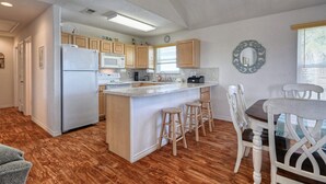 A spacious kitchen with wooden cabinets, a central island with stools, a refrigerator, and a microwave. - Beautiful island paradise only 6 blocks to the beach (Galveston)