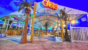 A tented outdoor area with a sign reading "CASIO" and palm trees. - Beautiful island paradise only 6 blocks to the beach (Galveston)