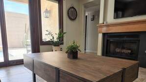 Een moderne keuken met een houten tafel, potplanten, een klok en een open haard.