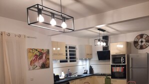Un salon moderne avec un canapé, une petite table et une cuisine en arrière-plan.