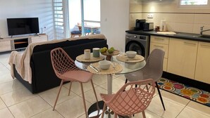Un salon moderne comprenant un canapé, un téléviseur et un coin repas avec des chaises et une table.