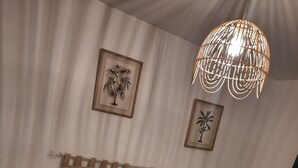 Une chambre à coucher avec un lit, deux tables de chevet, un luminaire suspendu et deux tableaux encadrés accrochés au mur.