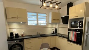 Une cuisine compacte équipée d’un lave-linge, d’une table à manger avec un set de table et d’un four à micro-ondes.