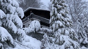 Un paysage enneigé avec un bâtiment doté d’un balcon et d’un escalier menant à celui-ci.