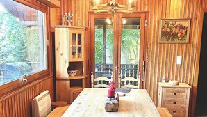 Une salle à manger en bois avec une grande table, des chaises et un lustre.