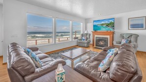 A living room with leather sofas, a coffee table, a fireplace, and a large TV.