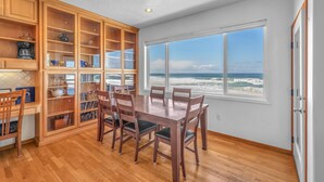 A dining area with a view of the ocean, wooden cabinets, and a large window.