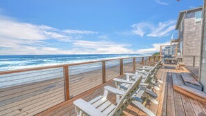 A wooden deck with lounge chairs overlooking the ocean.
