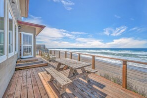 A wooden deck with picnic tables overlooking the ocean.