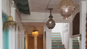 A hallway with a staircase, potted plants, and hanging lamps. - Sayulita Central Hotel (Sayulita)