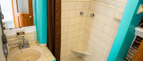 Une salle de bain équipée d’un lavabo, d’un miroir et d’une zone douche.