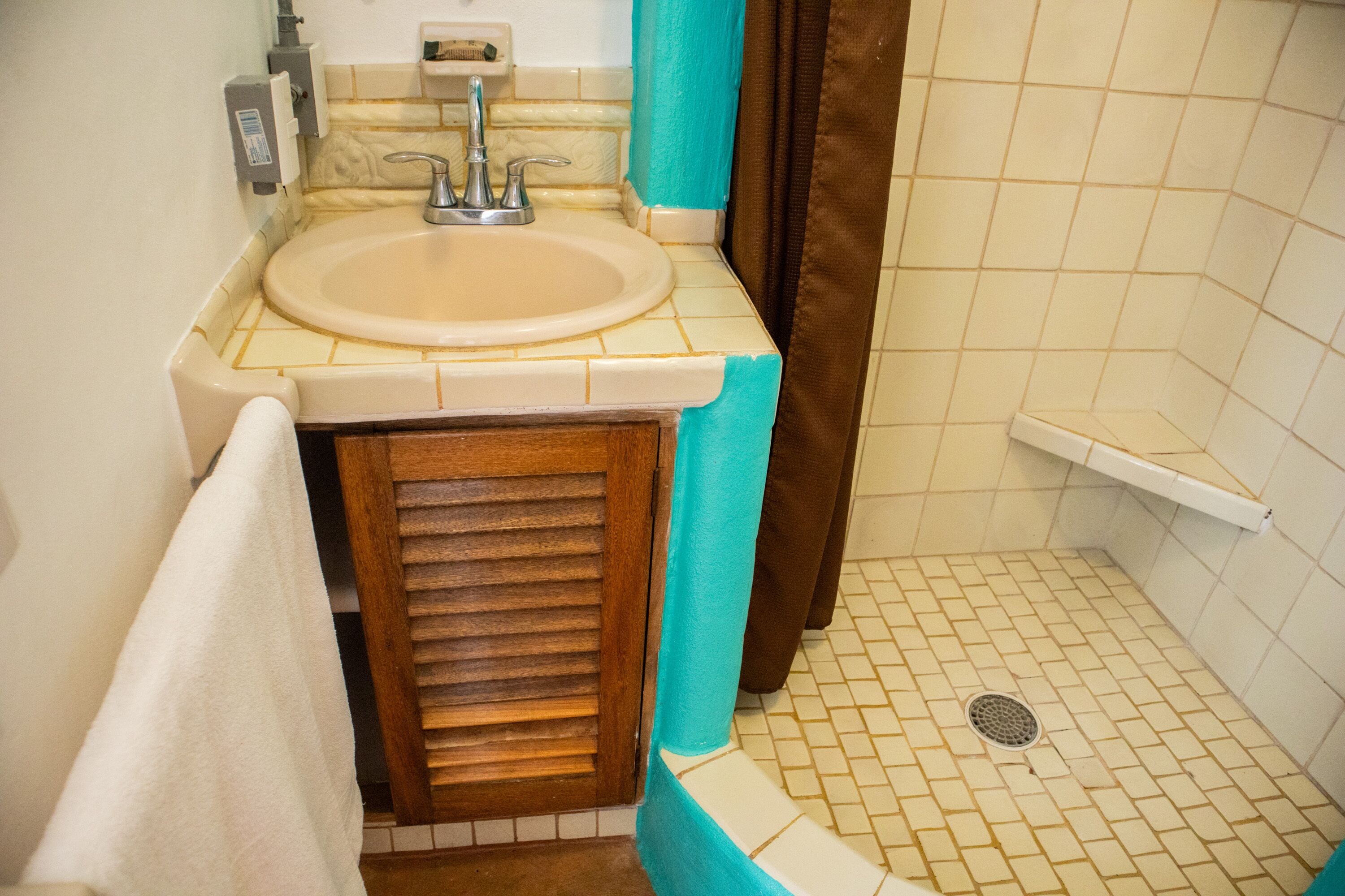 A bathroom with a sink, a shower, and a tiled floor.
