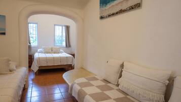 Un dormitorio con dos camas, un ventanal grande y una pintura de playa.