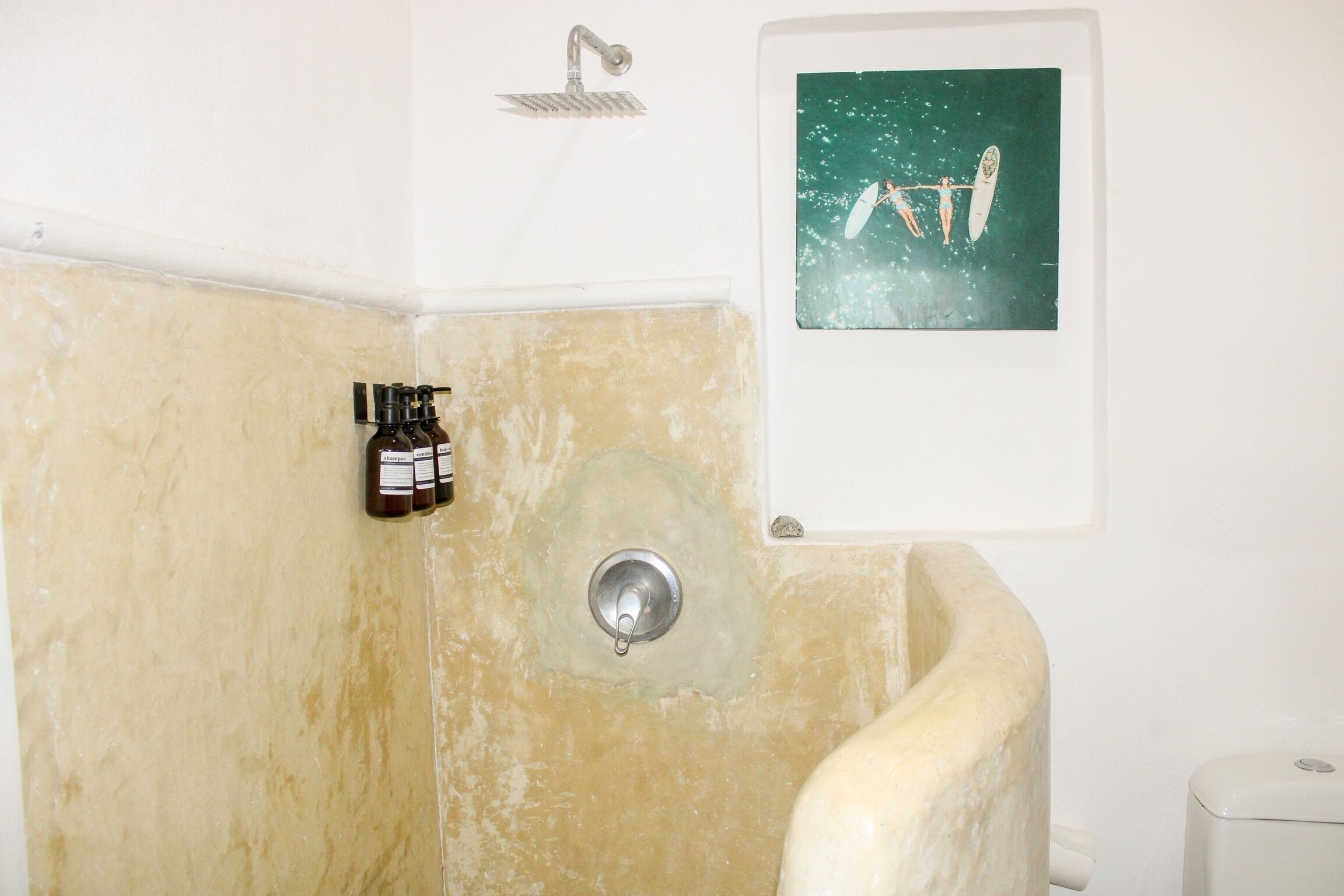Een badkamer met een douche, een wastafel en een aan de muur hangend schilderij.