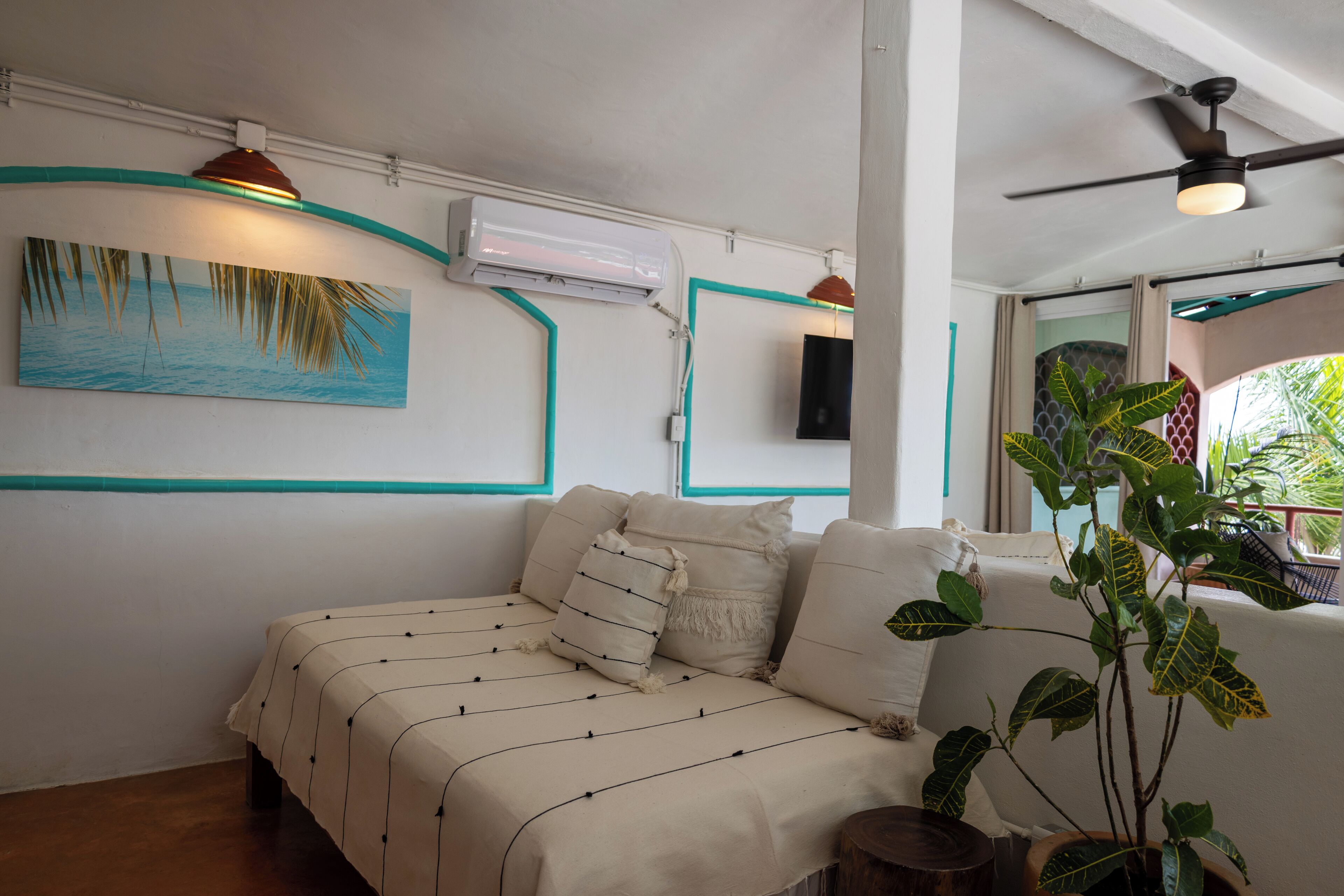 Un dormitorio con cama, unidad de aire acondicionado, luces empotradas, un cuadro y una planta en maceta.