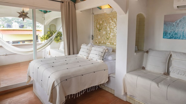 A bedroom with a bed, a hammock, and a view of the outside. - Sayulita Central Hotel (Sayulita)