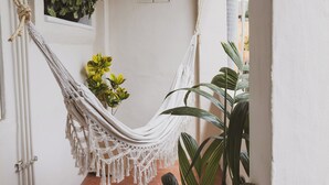 A narrow hallway with a white wall, a macramé hammock, a star-shaped hanging ornament, and a potted plant. - Sayulita Central Hotel (Sayulita)