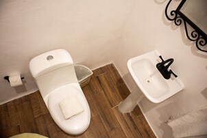 Baño con inodoro, lavamanos y suelo de madera.