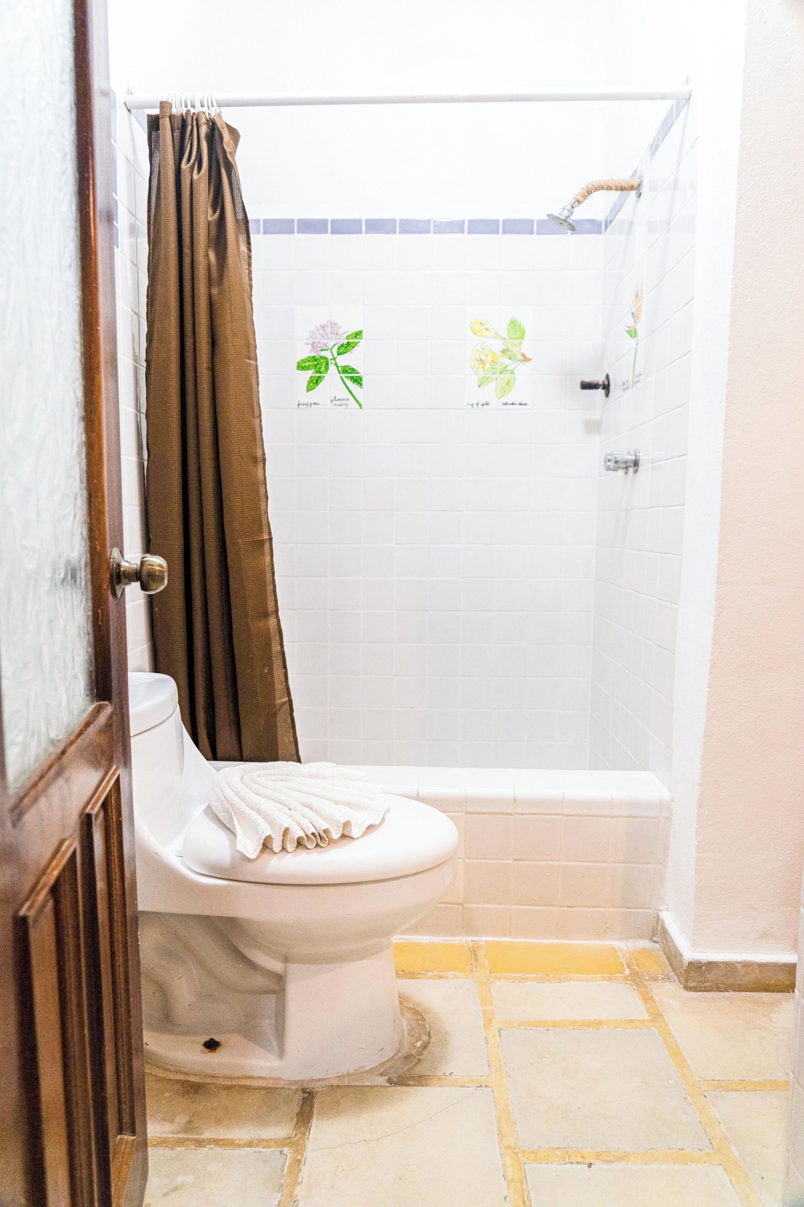 A bathroom with a toilet, shower, and tiled walls.
